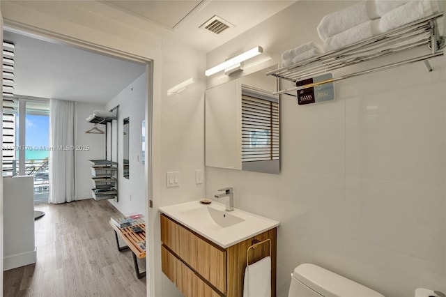 bathroom featuring toilet, vanity, visible vents, and wood finished floors