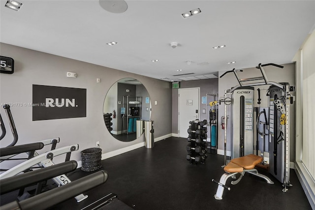 exercise room with baseboards, arched walkways, and recessed lighting
