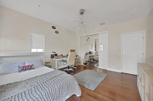 bedroom featuring baseboards, a closet, wood finished floors, and visible vents
