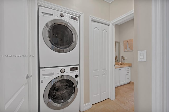 laundry area with laundry area, baseboards, stacked washing maching and dryer, and light tile patterned floors