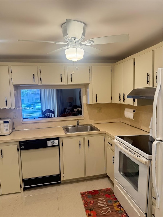 kitchen featuring light tile patterned flooring, white appliances, light countertops, under cabinet range hood, and a sink