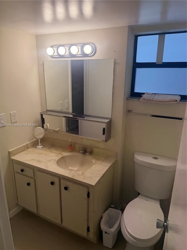 half bath featuring vanity, tile patterned flooring, and toilet