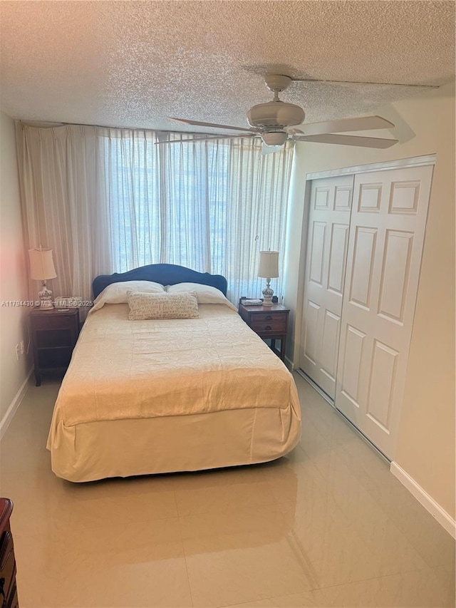 bedroom with a closet, baseboards, a ceiling fan, and a textured ceiling