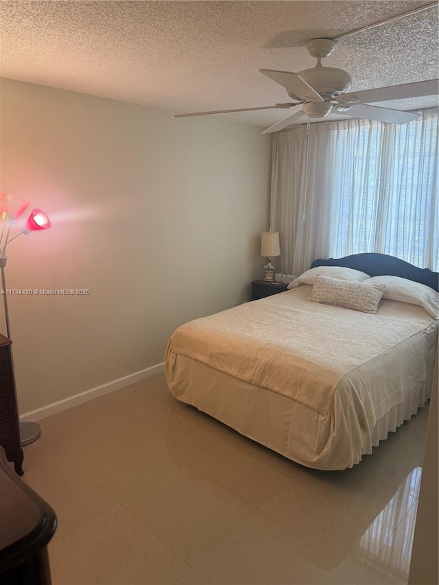 tiled bedroom with baseboards, a ceiling fan, and a textured ceiling