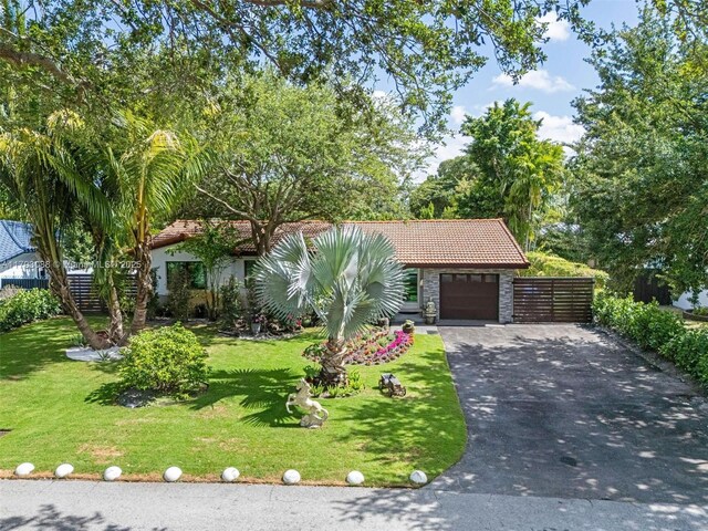 480 NW 88th Ter, El Portal, FL 33150 - view of front of house featuring driveway, a tile roof, a front yard, and stone siding