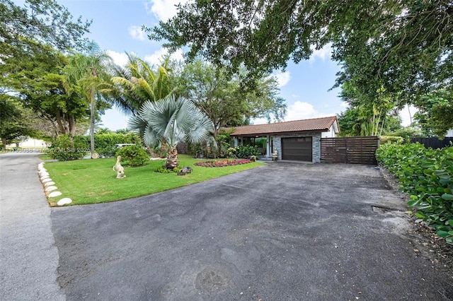 view of front of property featuring a garage, fence, a front yard, and aphalt driveway