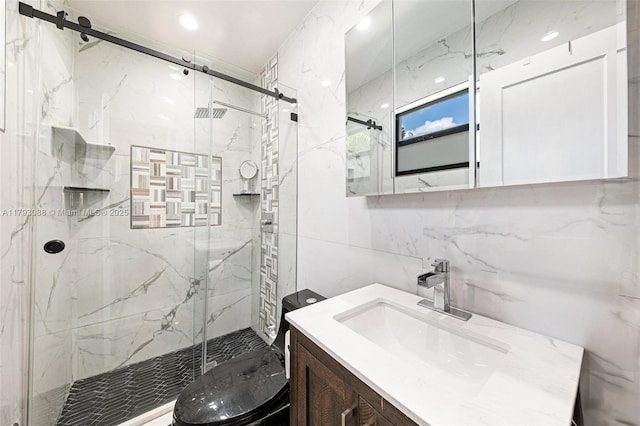 full bathroom with vanity, a marble finish shower, toilet, and tile walls