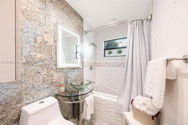 bathroom with tile walls, toilet, and tiled shower / bath combo