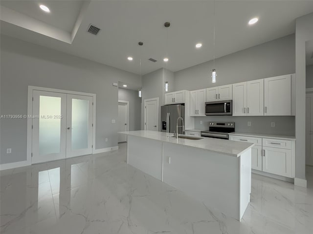 417 Paddock St, Lehigh Acres, FL 33974 - kitchen featuring appliances with stainless steel finishes, a sink, white cabinets, baseboards, and a kitchen island with sink