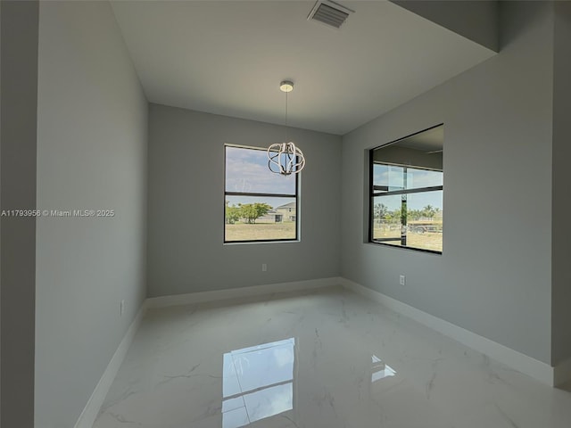 417 Paddock St, Lehigh Acres, FL 33974 - empty room featuring baseboards, light marble finish floors, and a chandelier