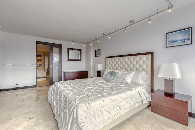 bedroom featuring track lighting, baseboards, and ensuite bathroom