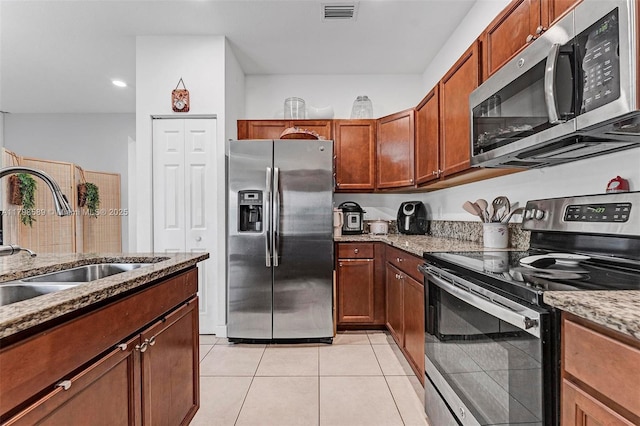 5301 Ellery Ter, West Palm Beach, FL 33417 - kitchen with light tile patterned flooring, light stone counters, a sink, stainless steel appliances, and visible vents