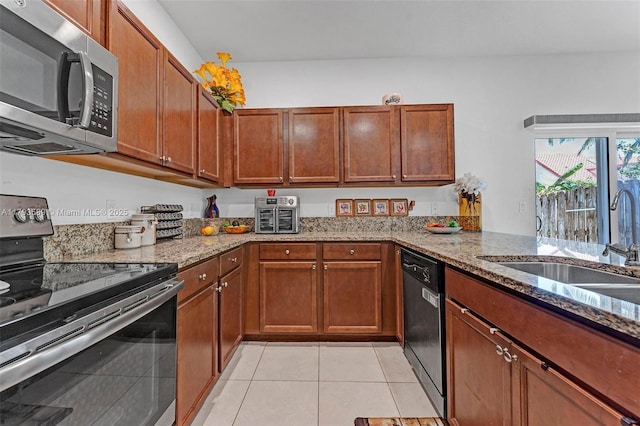 5301 Ellery Ter, West Palm Beach, FL 33417 - kitchen with light stone counters, a sink, brown cabinetry, stainless steel appliances, and light tile patterned floors