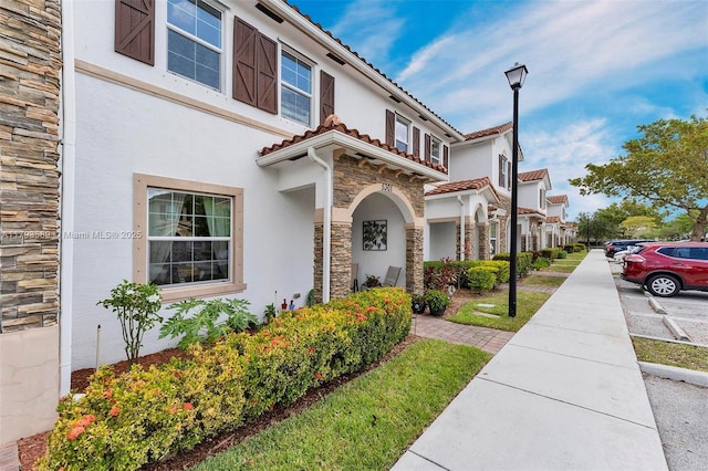 5301 Ellery Ter, West Palm Beach, FL 33417 - view of front facade with stucco siding, a tile roof, and stone siding