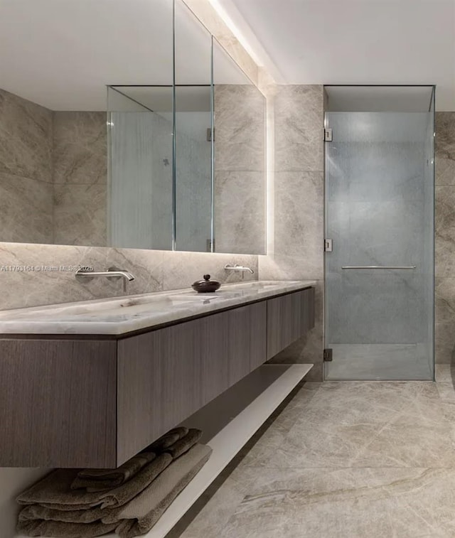 full bathroom with double vanity, tile walls, a stall shower, and a sink