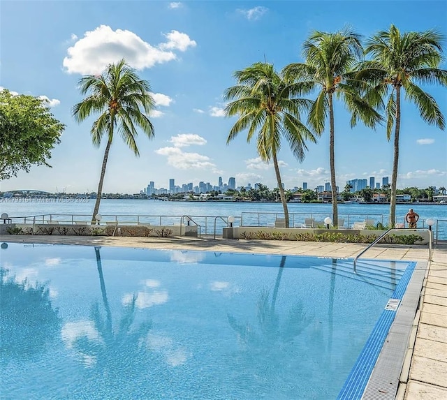 community pool featuring a water view, fence, and a city view