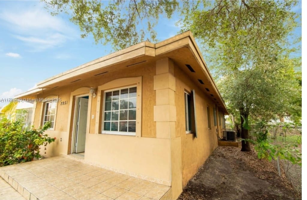 2951 NW 57th St, Miami, FL 33142 - view of side of home featuring a patio, central AC, fence, and stucco siding