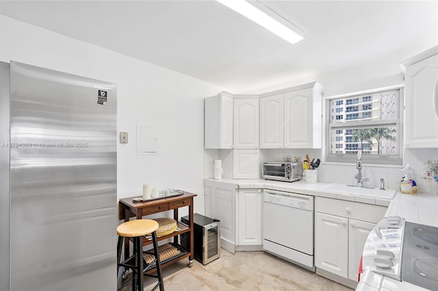 kitchen with white dishwasher, a sink, white cabinets, electric stove, and tile counters