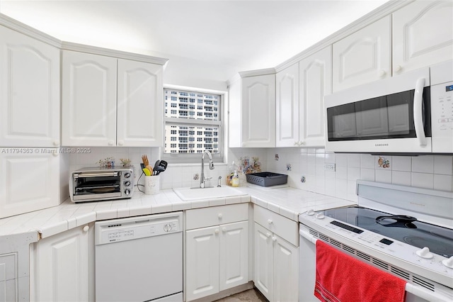 kitchen featuring a toaster, white appliances, white cabinetry, a sink, and backsplash