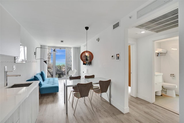dining area with visible vents, light wood-style flooring, and baseboards