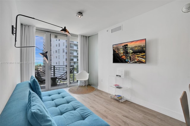 living area with baseboards, wood finished floors, and visible vents