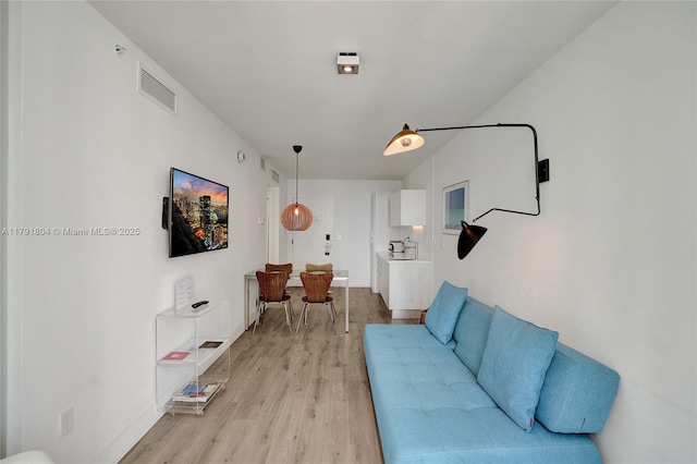 living room with baseboards, light wood-type flooring, and visible vents