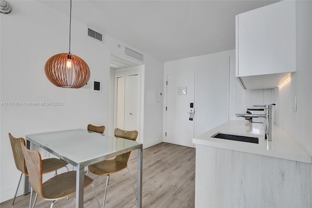 dining space with visible vents, attic access, and light wood-style flooring