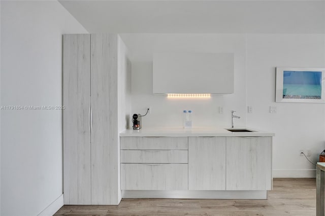 interior space with a sink, baseboards, and light wood-style flooring