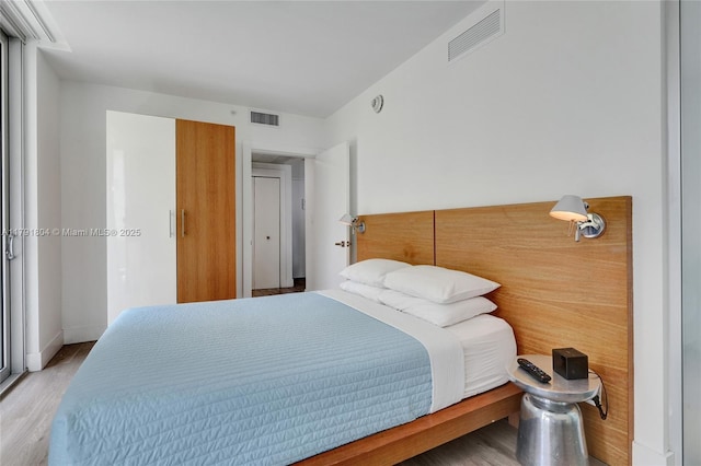 bedroom featuring baseboards, wood finished floors, and visible vents