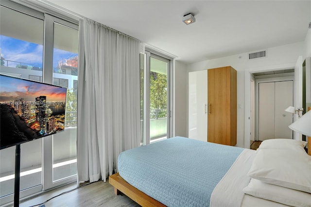 bedroom featuring access to outside, wood finished floors, and visible vents