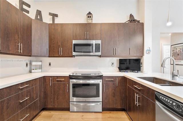 1371 Canary Island Dr, Weston, FL 33327 - kitchen featuring dark brown cabinetry, a sink, light countertops, light wood finished floors, and stainless steel appliances