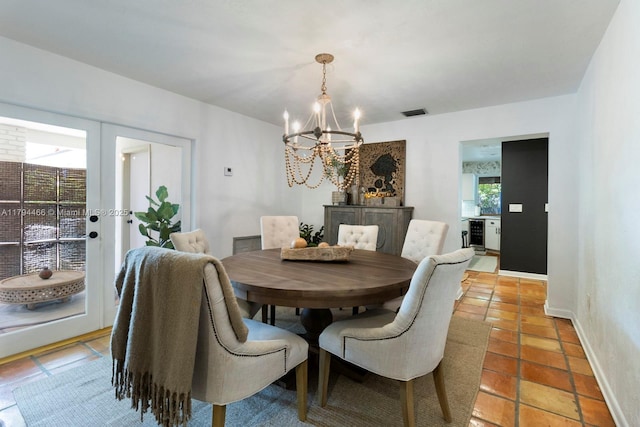 dining space with light tile patterned flooring, baseboards, an inviting chandelier, and visible vents