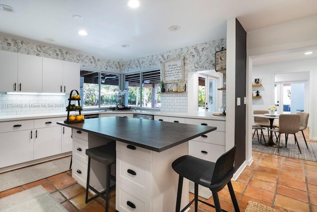 kitchen with white cabinetry, tasteful backsplash, and a kitchen bar