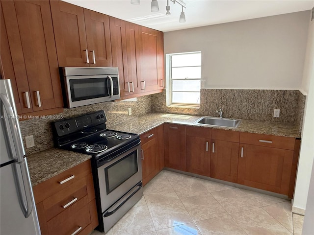 kitchen featuring brown cabinets, appliances with stainless steel finishes, a sink, and tasteful backsplash