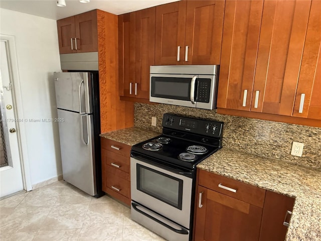 kitchen with backsplash, stainless steel appliances, light stone counters, and brown cabinetry