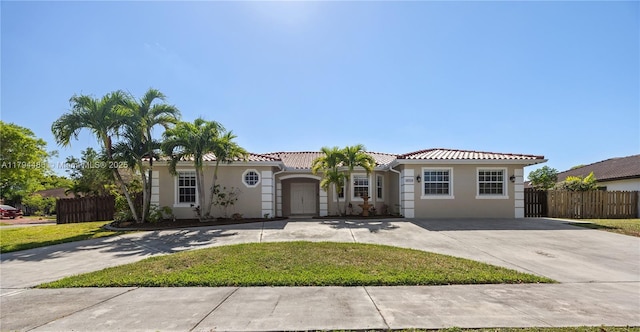 mediterranean / spanish home featuring fence, curved driveway, stucco siding, and a tiled roof