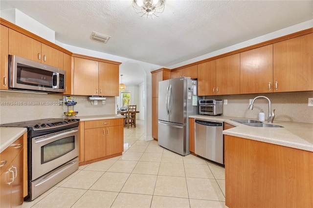 kitchen with decorative backsplash, visible vents, a sink, light tile patterned floors, and stainless steel appliances