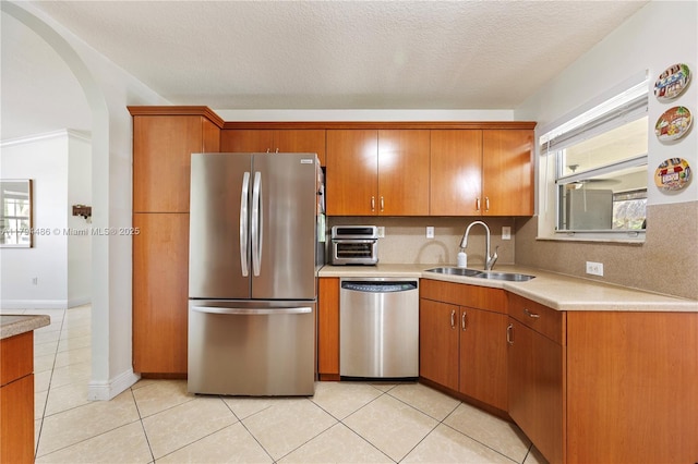 kitchen featuring a sink, light countertops, stainless steel appliances, and arched walkways
