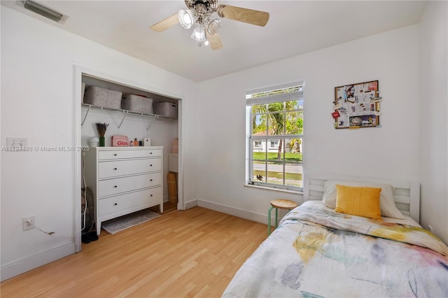 bedroom featuring ceiling fan, light wood-style flooring, baseboards, visible vents, and a closet