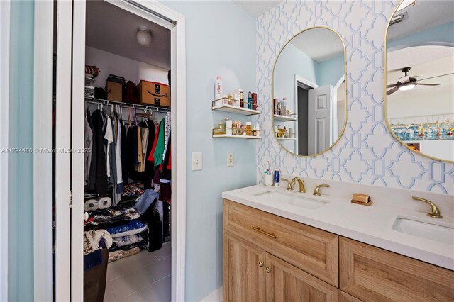 bathroom with double vanity, a sink, a walk in closet, and ceiling fan