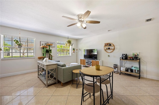 living area featuring ceiling fan, a textured ceiling, visible vents, light tile patterned floors, and baseboards