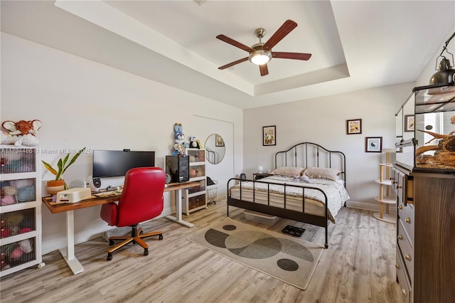 bedroom featuring baseboards, a tray ceiling, and wood finished floors