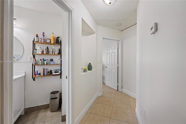 corridor with baseboards and light tile patterned flooring