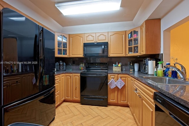 kitchen with a sink, decorative backsplash, black appliances, and glass insert cabinets