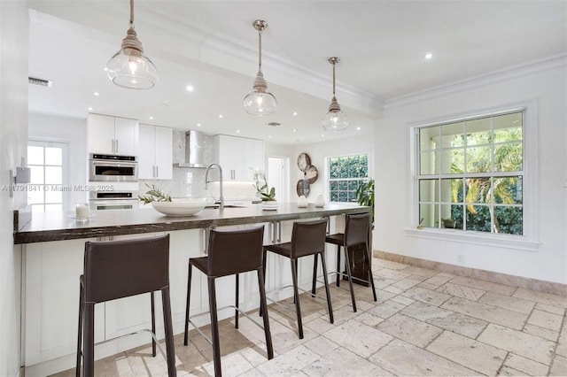 1161 Sunset Dr, Coral Gables, FL 33143 - kitchen featuring a sink, dark countertops, white cabinets, hanging light fixtures, and a breakfast bar