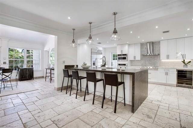 1161 Sunset Dr, Coral Gables, FL 33143 - kitchen with wine cooler, wall chimney range hood, white oven, crown molding, and backsplash