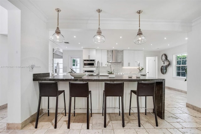 1161 Sunset Dr, Coral Gables, FL 33143 - kitchen with wall chimney exhaust hood, baseboards, a sink, stone tile flooring, and healthy amount of natural light