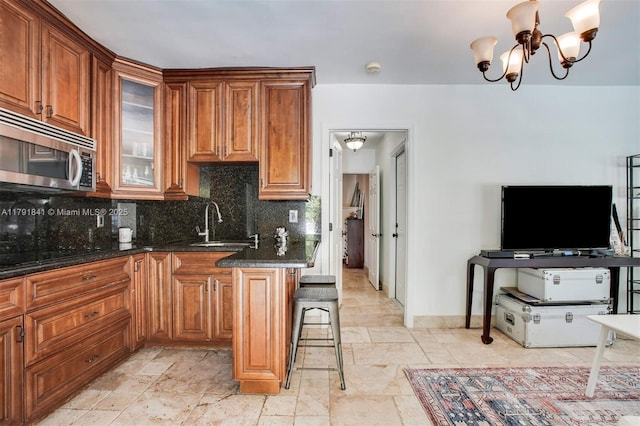 1161 Sunset Dr, Coral Gables, FL 33143 - kitchen with stainless steel microwave, a sink, decorative backsplash, stone tile flooring, and brown cabinets