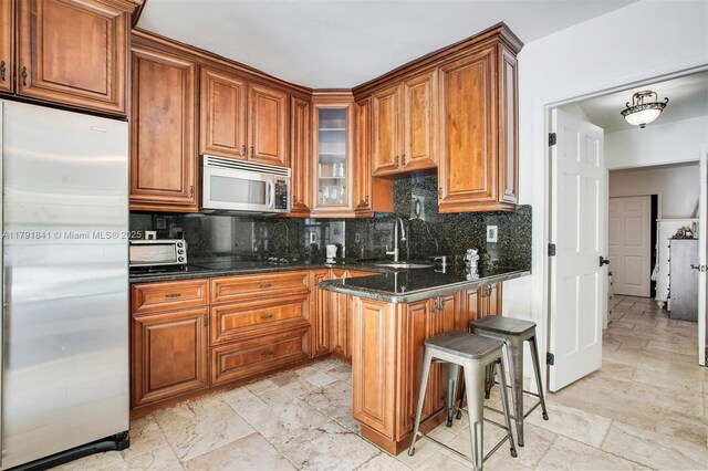 1161 Sunset Dr, Coral Gables, FL 33143 - kitchen featuring stainless steel appliances, a sink, brown cabinetry, tasteful backsplash, and glass insert cabinets