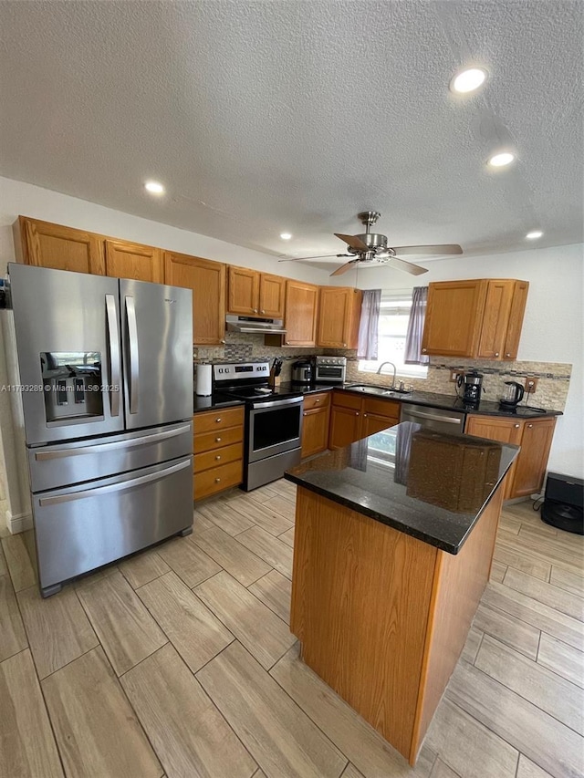 8588 NW 27th Dr, Coral Springs, FL 33065 - kitchen featuring decorative backsplash, wood finish floors, under cabinet range hood, a sink, and appliances with stainless steel finishes